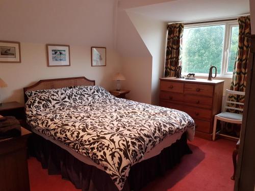 a bedroom with a bed and a dresser and a window at House On The Hill in Little Massingham