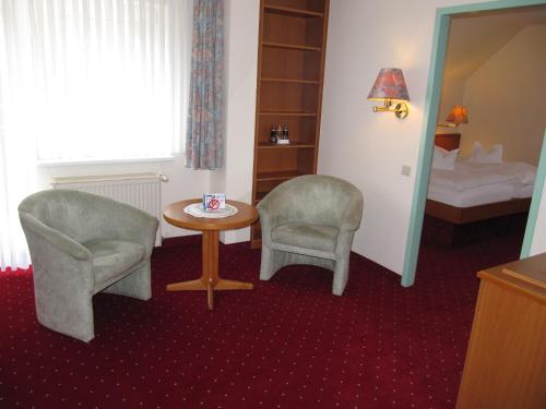 a room with two chairs and a table and a bed at Hotel Pension Marie-Luise, Hotel garni in Bad Bevensen