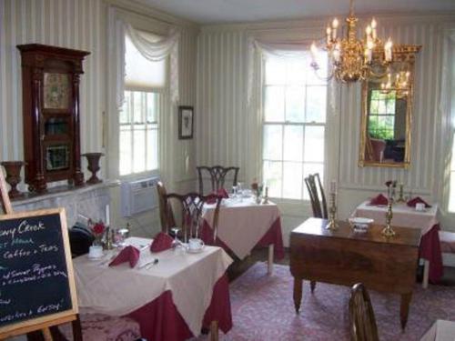 una sala da pranzo con due tavoli e un lampadario a braccio di The Inn at Stony Creek a Warwick