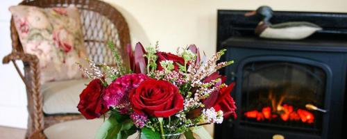a vase with red roses in front of a fireplace at The Inn at Stony Creek in Warwick