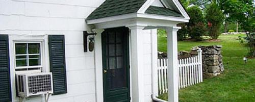 a white house with a black door and a fence at The Inn at Stony Creek in Warwick