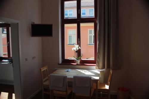 einen Esstisch mit einer Blumenvase am Fenster in der Unterkunft Gästehaus INNFernow in Fürstenberg-Havel