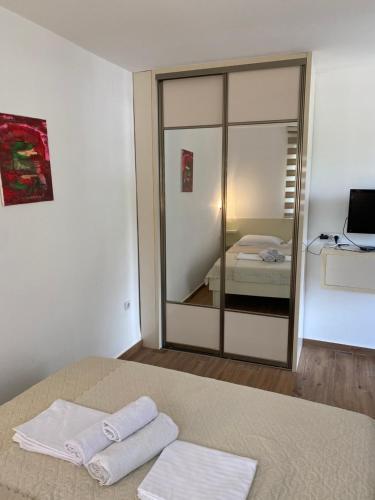 a bedroom with a mirror and two towels on a bed at Apartments Boss in Budva