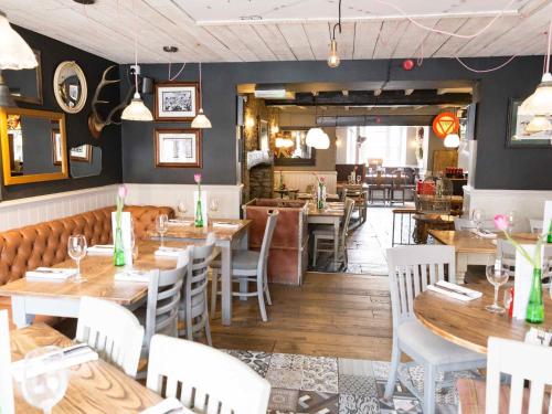a restaurant with wooden tables and white chairs at The Plough Bicester in Bicester