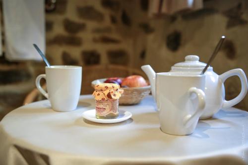 uma mesa com duas chávenas e um bule de chá e uma taça de fruta em Les Jardins de l'Abbaye em Simiane-la-Rotonde
