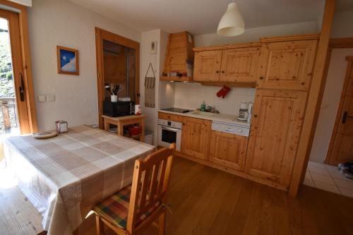 eine Küche mit Holzschränken und einem Tisch mit Stühlen in der Unterkunft VAUJANYLOCATIONS - Le Jardin Alpin in Vaujany