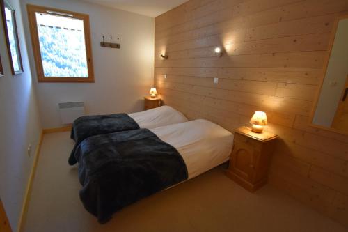 a bedroom with two beds in a wooden wall at VAUJANYLOCATIONS - Le Jardin Alpin in Vaujany