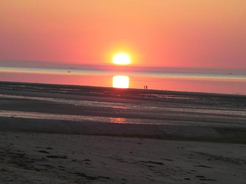 - un coucher de soleil sur la plage avec des personnes se promenant sur la plage dans l'établissement Duplex Croisette Juno Beach, à Bernières-sur-Mer