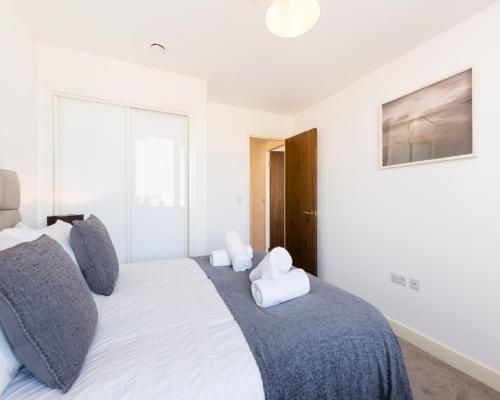 a bedroom with a large white bed with gray pillows at KCS Luxury Apartment - Broad Street Birmingham in Birmingham