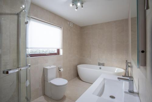 a bathroom with a toilet and a tub and a sink at Keef Halla Country House in Crumlin