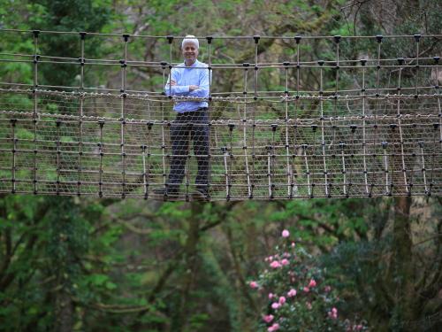 a person standing on a suspension bridge at Kells Bay House and Gardens in Kells