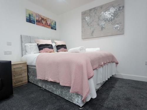 a bedroom with a bed with pink blankets and pillows at City Hospital Apartments in Leeds