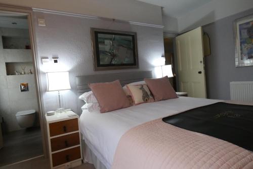 a bedroom with a large white bed with pink pillows at Kentwood Guest House in Arnside