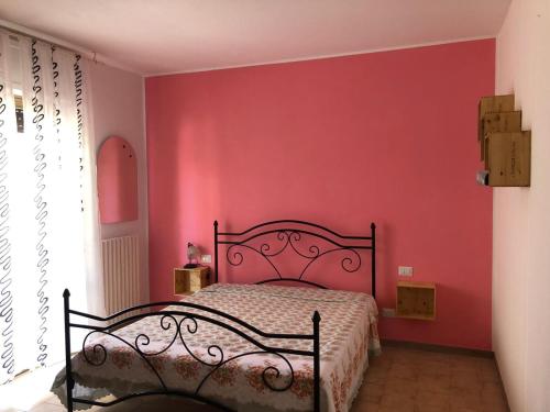 1 dormitorio con 1 cama con pared roja en Appartamento Gemma, en Martinsicuro