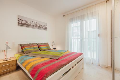 a bedroom with a bed with a colorful striped blanket at Apartments Villa Swissmonte in Herceg-Novi