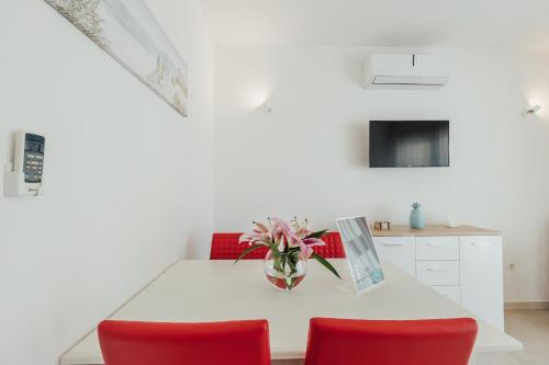 a white table with red chairs and a vase of flowers at Apartments Villa Swissmonte in Herceg-Novi