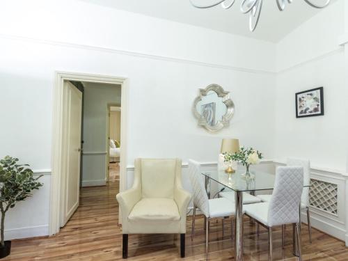 comedor con mesa de cristal y sillas blancas en Comfortable One Bed in Central, en Londres