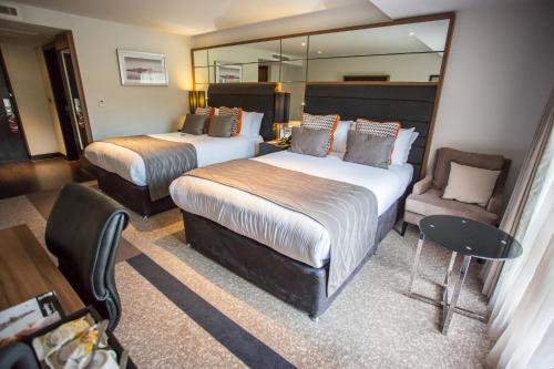 a hotel room with two beds and a chair at Crowne Plaza Gerrards Cross by IHG in Beaconsfield