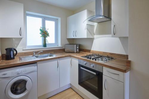 a white kitchen with a sink and a stove at Host & Stay - The Limes in Harrogate