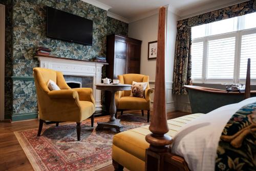 a bedroom with a fireplace and chairs and a television at Bear Of Burton in Christchurch