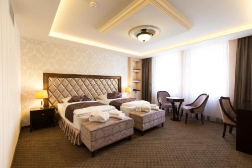 a hotel room with two beds and a table and chairs at Hotel Dvorana in Karlovy Vary