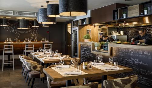 a restaurant with wooden tables and chairs and a bar at Girandella Resort, Valamar Collection in Rabac