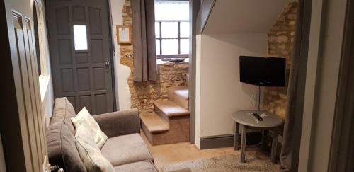 a living room with a couch and a television at The Kings Arms Hotel in Stow on the Wold