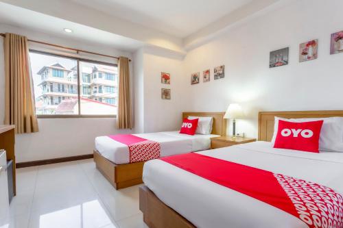 two beds in a hotel room with red and white pillows at Super OYO 1096 Winner Inn Hotel in Chiang Mai