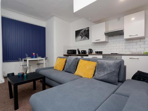 Kirkstall House في ليدز: غرفة معيشة مع أريكة زرقاء ووسائد صفراء