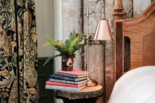 a stack of books on a table next to a bed at Bear Of Burton in Christchurch