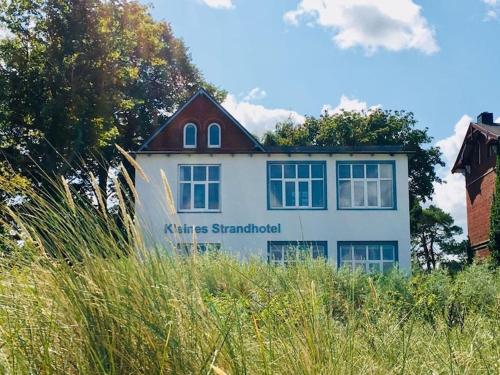 a white house with a sign on the side of it at Kleines Strandhotel in Niendorf