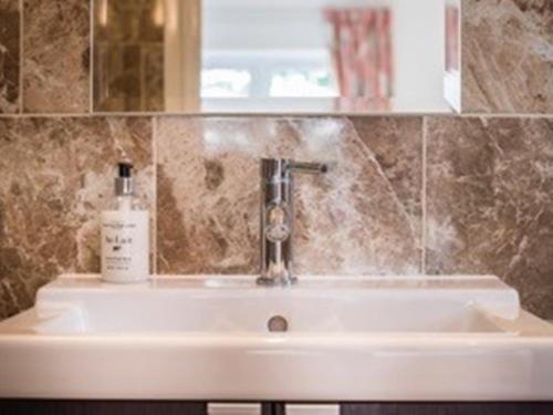 a bathroom sink with a bottle of soap on it at Knole B&B in Sevenoaks
