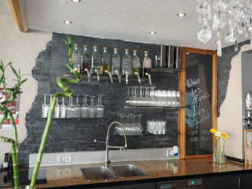 a bar with a wall with bottles and a sink at Weincafé Korkenzieher in Briedel