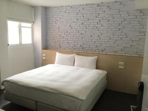 a bedroom with a white bed with a brick wall at Taimali Hotel in Taimali