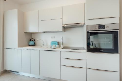 a white kitchen with white cabinets and a microwave at Apartments Villa Swissmonte in Herceg-Novi