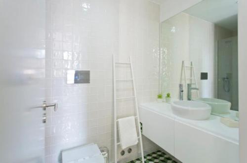 La salle de bains blanche est pourvue d'un lavabo et d'un miroir. dans l'établissement A da Maria Ildefonso, à Porto
