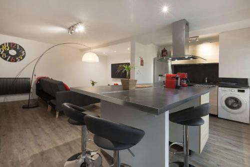 a kitchen with a counter and chairs in a room at La Dimière - Appartements de standing en hyper-centre - Louviers in Louviers