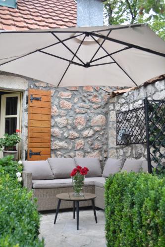 a patio with a couch and a table and an umbrella at Apartman L&M in Cetinje
