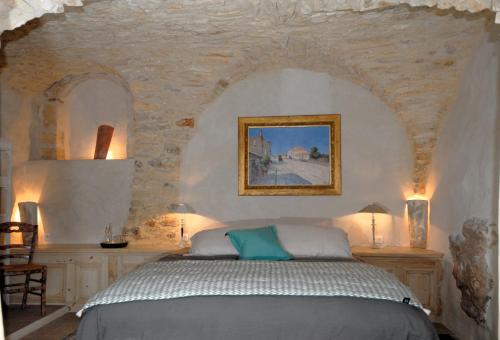 une chambre avec un lit dans un mur de pierre dans l'établissement La Maison Blanche Uzès, à La Bastide-dʼEngras