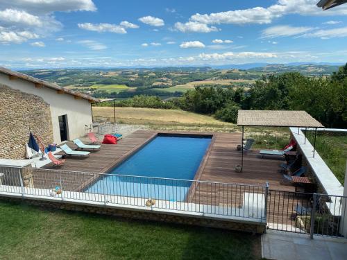 a swimming pool on a wooden deck next to a house at La Maison de Paul & Margaux in Châteauneuf-de-Galaure