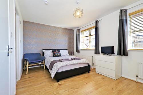 a bedroom with a bed and a chair and a television at Harlinger Lodge Annexe in London