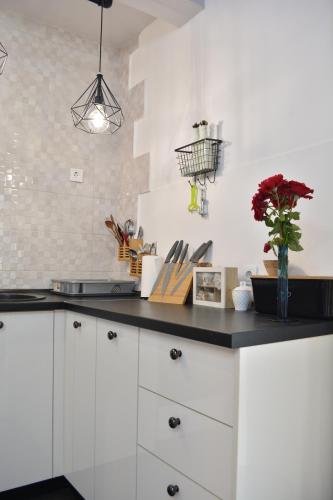 a kitchen with white cabinets and a black counter top at Apartman L&M in Cetinje