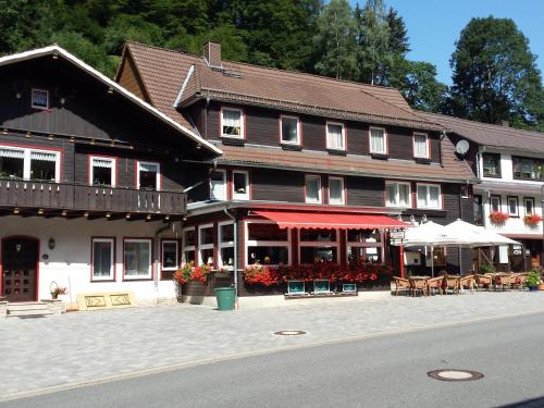 a large wooden building with tables and chairs on a street at Landgasthof Kleine Kommode in Zorge