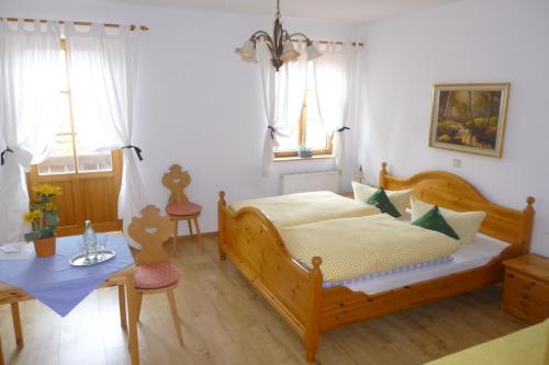 Schlafzimmer mit einem Bett, einem Tisch und Fenstern in der Unterkunft Landgasthof Berg in Eurasburg