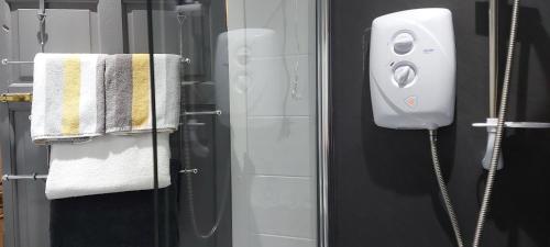 a bathroom with a shower with a phone on the wall at LAWFIELD R&R in West Kilbride