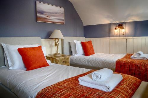 a hotel room with two beds with towels on them at The Lansdowne Cottage in Bourton on the Water