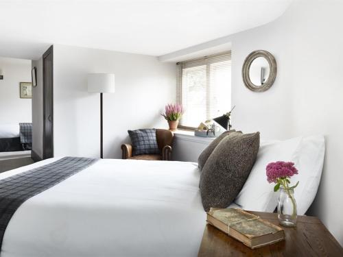 a bedroom with a white bed with a table and a mirror at The Masons Arms in Cirencester