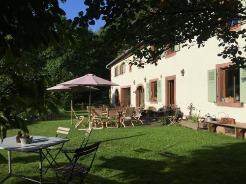 a backyard with a table and chairs and an umbrella at La Pierre d'Eau in Fréland