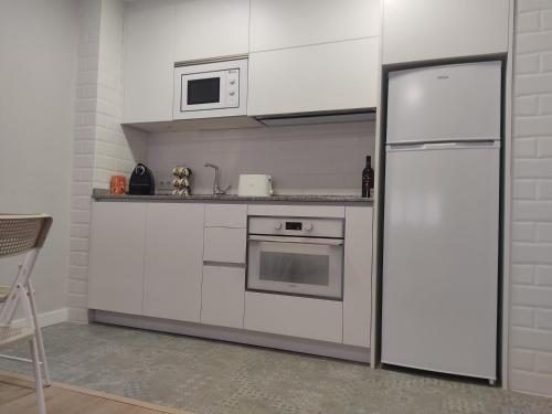 a white kitchen with a refrigerator and a microwave at Las Ildas in Anguiano
