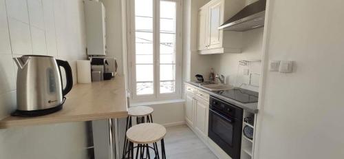 une cuisine avec un évier et un comptoir avec des tabourets dans l'établissement APPARTEMENT CANNES MONTFLEURY, à Cannes